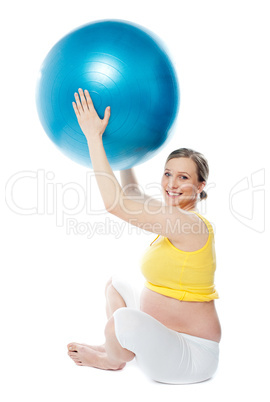 Smiling pregnant woman with a ball