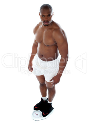 Muscular man standing on electronic weighing machine