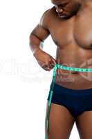 Muscular man measuring his waist
