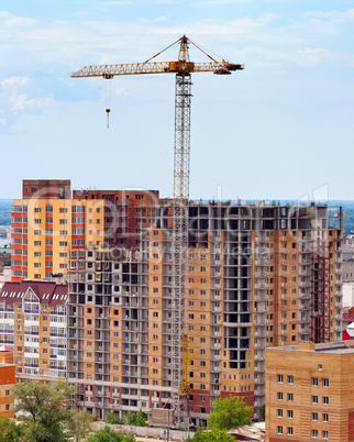 Building under construction with crane over blue sky background