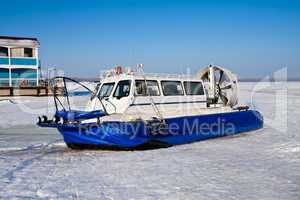 Hovercraft crossing frozen river against a blue sky