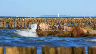 Buhnen in der Ostsee mit Segelbooten und Windpark im Hintergrund