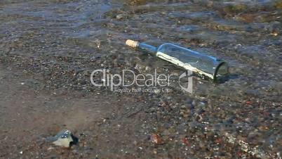 Flaschenpost zwischen Felsen und Wasser am Strand