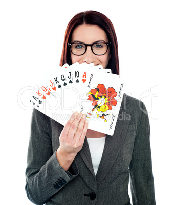 Corporate lady hiding her smile with playing cards