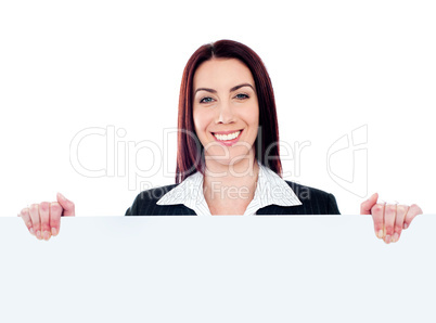 Young beautiful woman standing behind billboard