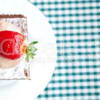 beautiful cake with strawberry on plaid fabric