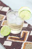 water with lemon and lime in a glass with ice on ethnic mat
