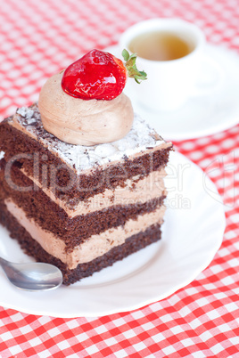 beautiful cake with strawberry and tea on plaid fabric