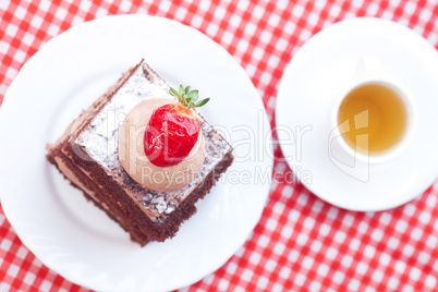 beautiful cake with strawberry and tea on plaid fabric