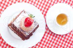 beautiful cake with strawberry and tea on plaid fabric