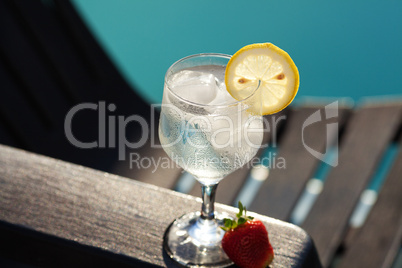 Swimming pool, lounge, a wine glass with ice, lemon and strawber