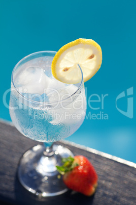 Swimming pool, lounge, a wine glass with ice, lemon and strawber