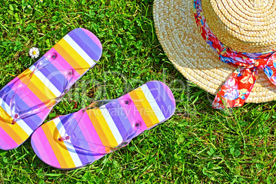 Colourful flip flops and a straw hat on the grass