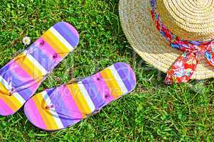 Colourful flip flops and a straw hat on the grass