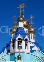 Cupolas of Russian orthodox church against blue sky.