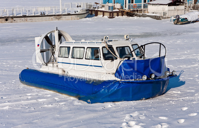Hovercraft crossing frozen river against a blue sky