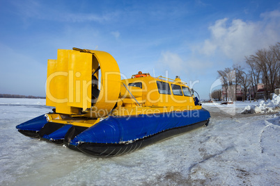 Hovercraft crossing frozen river against blue sky