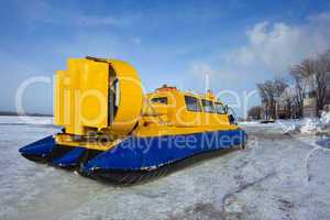 Hovercraft crossing frozen river against blue sky