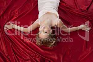 Pretty young woman lying on silk sheets
