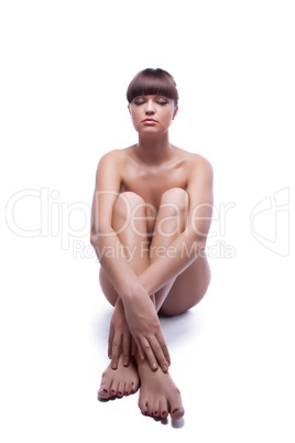 Nude young woman sitting on floor