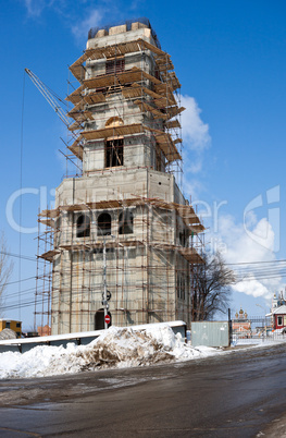 Tower building under construction with crane over blue sky backg