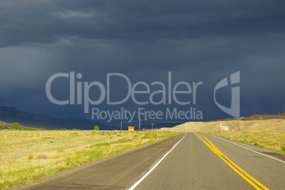 Sunny road into dark skies near Buffalo Bill Reservoir, Wyoming