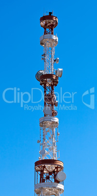 Telecommunication tower with antennas over a blue sky.