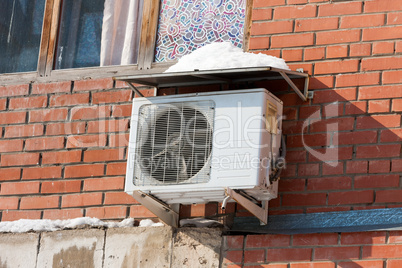 Air conditioning heat pump mounted on brick wall.