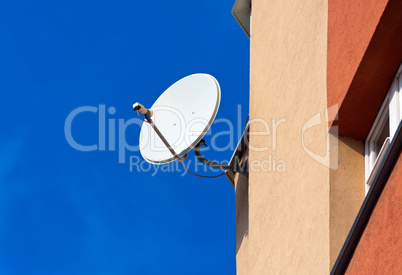 Satellite Dish mounted on  brick wall against blue sky backgroun