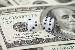 Two dice laying over a pile of money