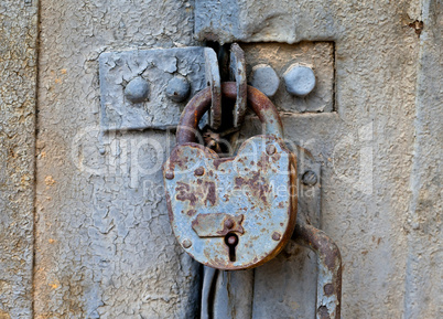 Rusty padlock on an old metal door
