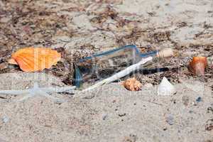 Flaschenpost am Strand mit Muscheln und Seestern
