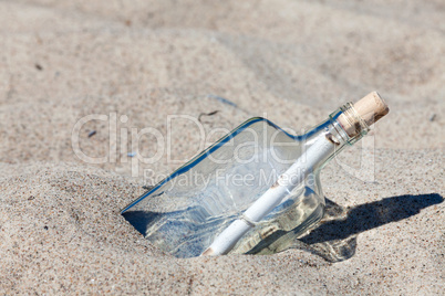 Flaschenpost steckt im Sand am Strand