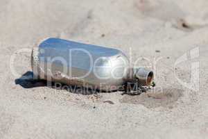 Wasser tropft aus einer Feldflasche im Sand