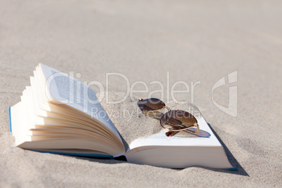 Sonnenbrille liegt auf Buch am Strand