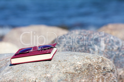 Sonnenbrille liegt auf einem Buch am Strand