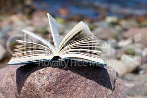 Aufgeschlagenes Buch liegt am Strand