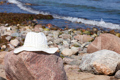 Damen Strohhut liegt am felsigen Strand der Ostsee