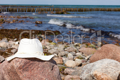 Damen Strohhut liegt am felsigen Strand der Ostsee