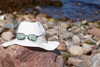 Strohhut mit Sonnenbrille liegen auf einen Felsen