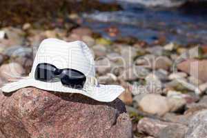 Strohhut mit Sonnenbrille liegen auf einen Felsen
