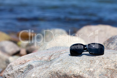 Sonnenbrille liegt auf einen Felsen ander Küste