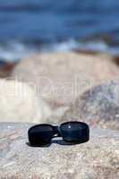 Sonnenbrille liegt auf einen Felsen ander Küste