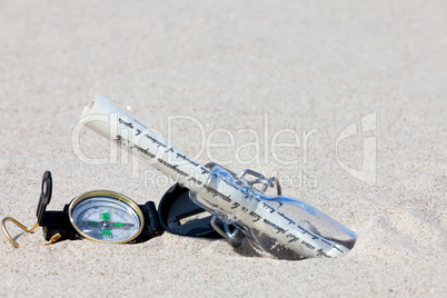 Flaschenpost mit Brief und Kompass im Sand