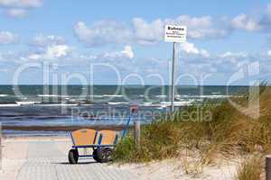 Bollerwagen steht allein am Wegesrand zum Strand