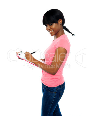 Smiling girl writing on clipboard