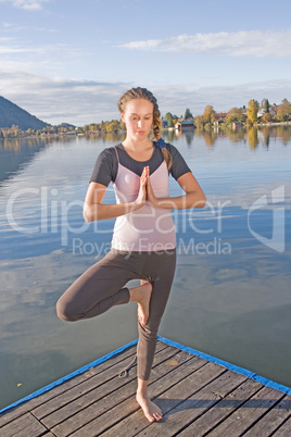 Junge Frau beim Yoga am See