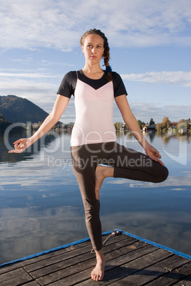 Junge Frau beim Yoga am See