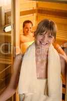 Smiling woman at sauna wrapped in towel