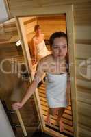 Exhausted woman leaving sauna in health spa